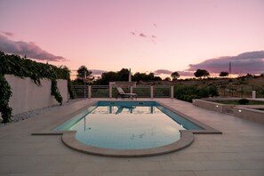 A swimming pool with a sunken center, surrounded by a tiled deck and a low wall with climbing plants. - Resort Villa San Lilin (Nerežišće)