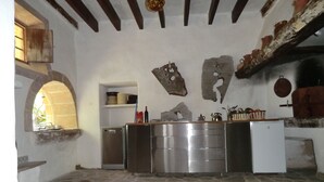 A rustic kitchen with stone flooring, a stainless steel refrigerator, and a white washing machine. - Son Barbut XVII, Family-friendly (Porreres)