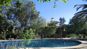A swimming pool surrounded by greenery and a stone building in the background. - Son Barbut XVII, Family-friendly (Porreres)