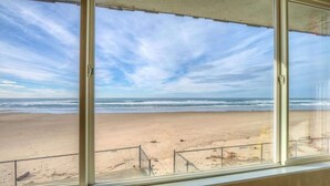 A beach view through a window with a metal railing in the foreground. - Retro Oceanfront Suite - Pool and Sauna - Second Floor - Sleeps 4 (Lincoln City)