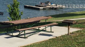 Un parque junto al lago con mesas de picnic y un muelle que se adentra en el agua.