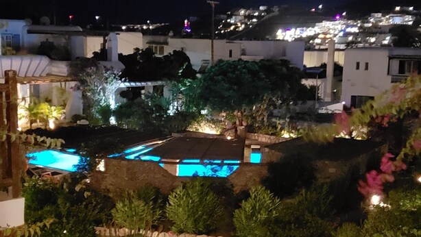 A nighttime view of a residential area with illuminated pathways and greenery. - Pleiades Villa, Near Ornos Beach (Mykonos)