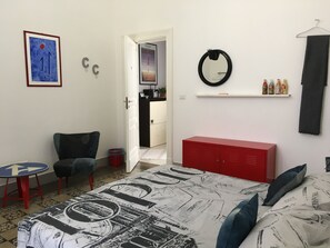 A bedroom with a bed, a red wardrobe, a round mirror, and a small table with chairs. - Home Design Stories (apartment 2-4 people) (Catania)
