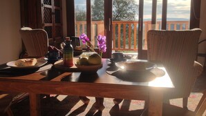 A wooden dining table with a view of the outdoors, a chair, a vase with flowers, and a pitcher. - Apartment with a Mountain View and Shared Pool (Montefrio)