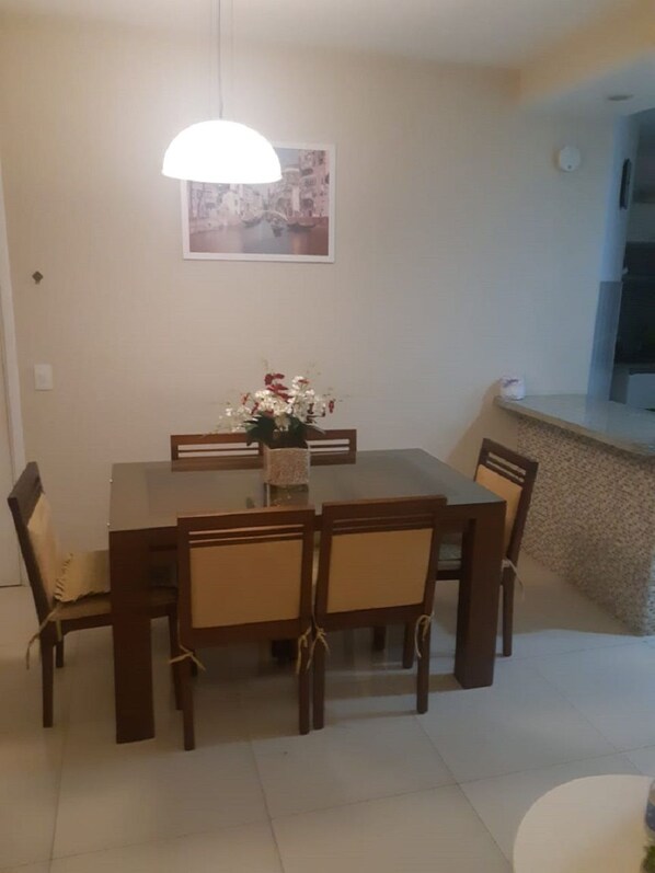 Uma área de refeições com uma mesa e cadeiras, um vaso com flores e um quadro na parede.