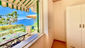 A balcony with a view of the sea, a table with a colorful tablecloth, and a white wardrobe. - Tramonto Praiano centre village (Praiano)
