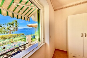 Un balcon avec vue sur la mer, une table recouverte dâune nappe colorĂ©e et une armoire blanche.