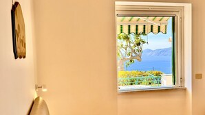 A room with a bed, a window with a view of the sea, and a lamp. - Tramonto Praiano centre village (Praiano)
