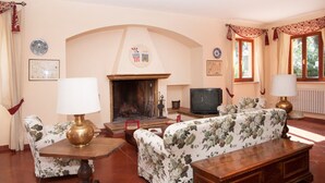 A living room with a fireplace, two sofas, a television, and a wooden coffee table. - Villa degli Scoiattoli, 200-m² villa for 8-10 people with park and swimming pool (Casette D'ete, FM)