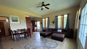 A spacious living area with a dining table, two couches, and a kitchen in the background.