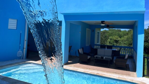 A blue building with a swimming pool and outdoor seating area.