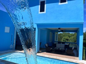 Ein blaues Gebäude mit Schwimmbecken und Sitzbereich im Freien.