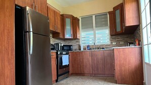 A kitchen with wooden cabinets, a stainless steel refrigerator, a microwave, and an oven.