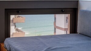 Un dormitorio con vista al océano, una ventana y una cama.