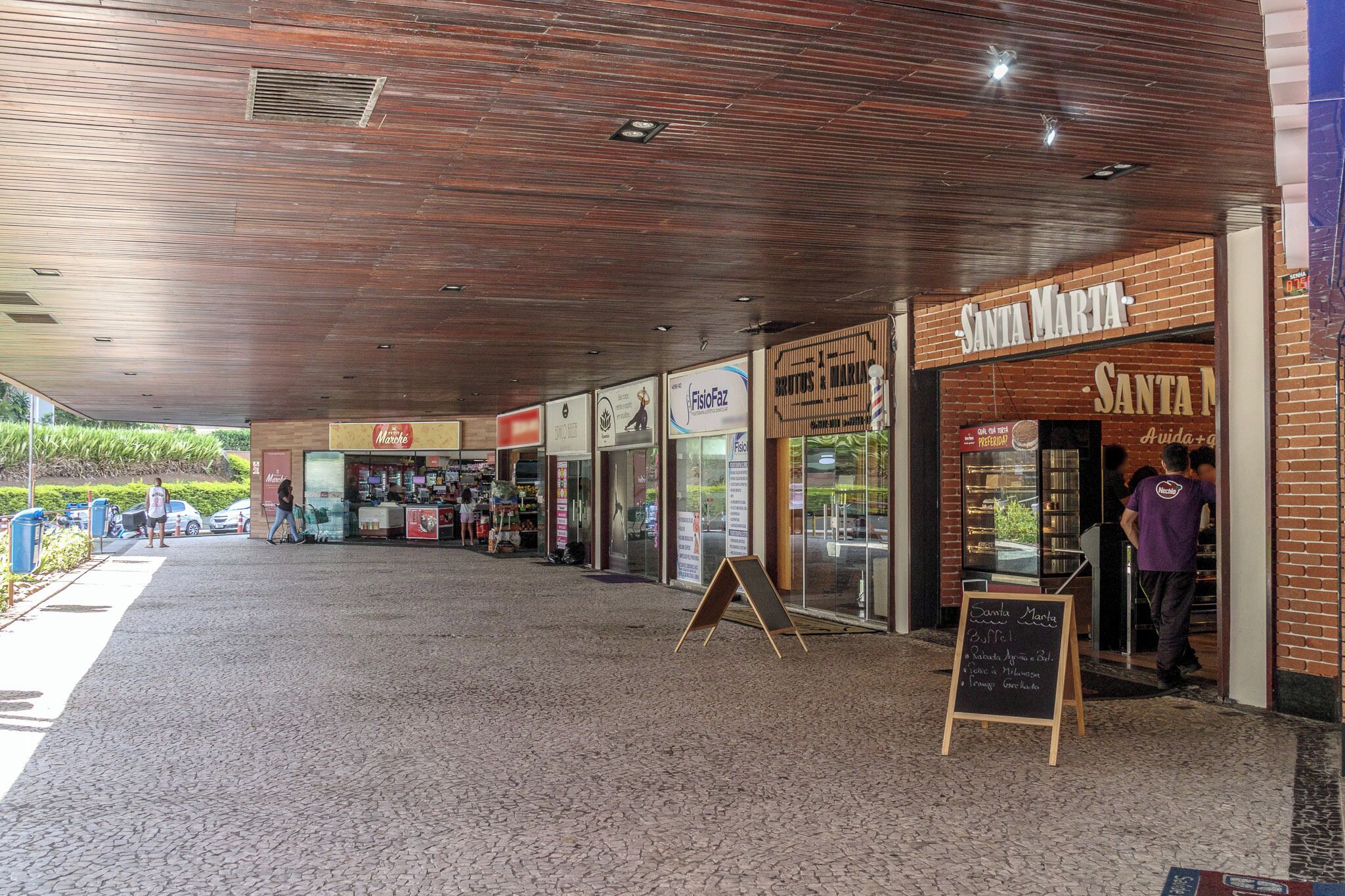 Un espace extérieur abrité, doté d’une façade en briques, d’une enseigne indiquant « Santa Marta » et d’un panneau noir annonçant « 3,50/1 ».