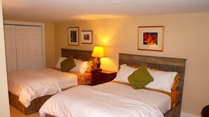 A hotel room with two beds, a wooden headboard, a nightstand with a lamp, and framed pictures on the wall. - Downtown Luxury Studio, Brevard NC (Brevard)