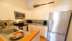 A modern kitchen with white cabinets, stainless steel appliances, and a wooden countertop. - Two Level Condo with all the Essentials, Thames St (Newport)