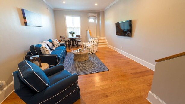 A living room with a sofa set, a coffee table, and a TV mounted on the wall. - Two Level Condo with all the Essentials, Thames St (Newport)