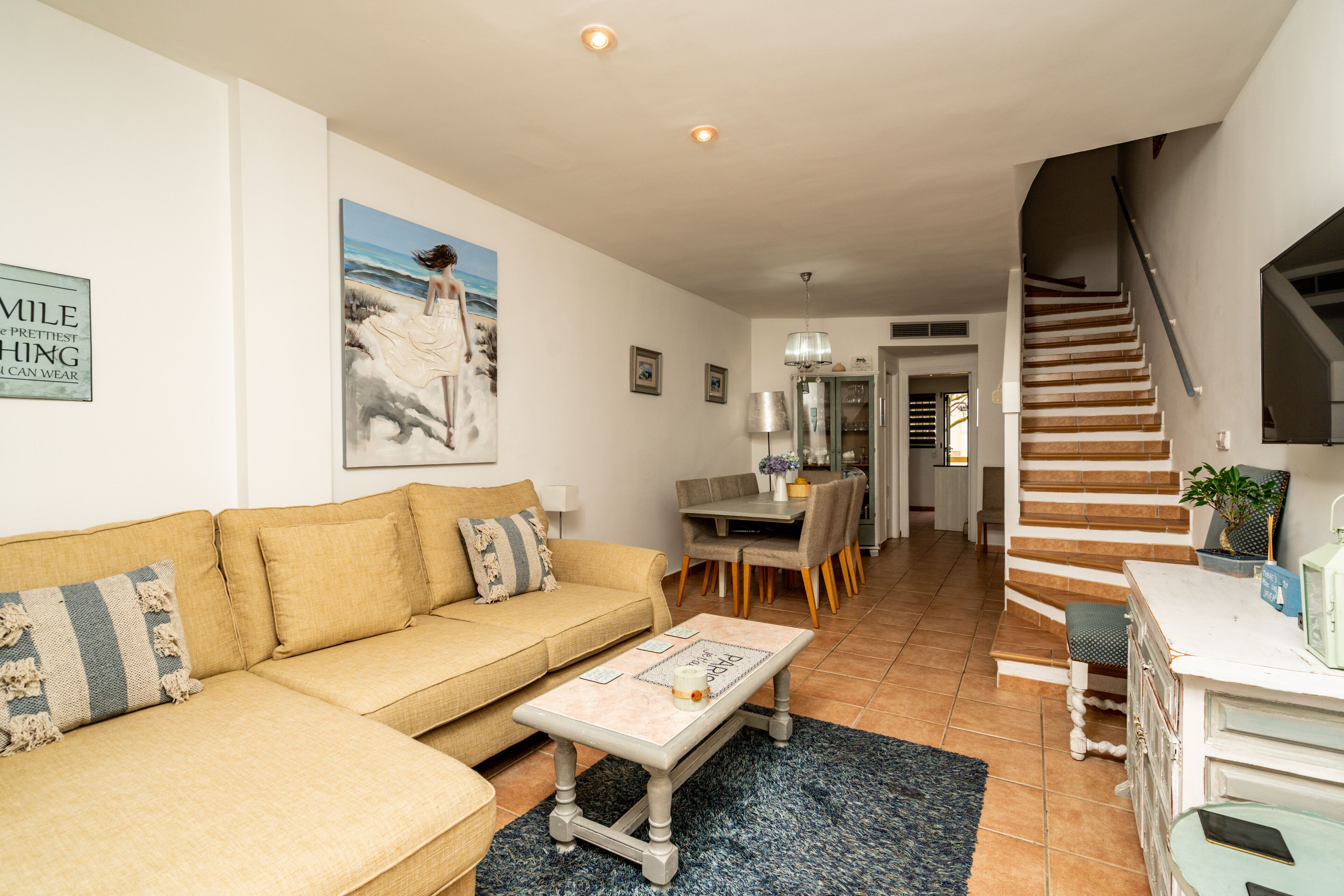 A living room with a sofa, coffee table, and a painting of a beach scene.
