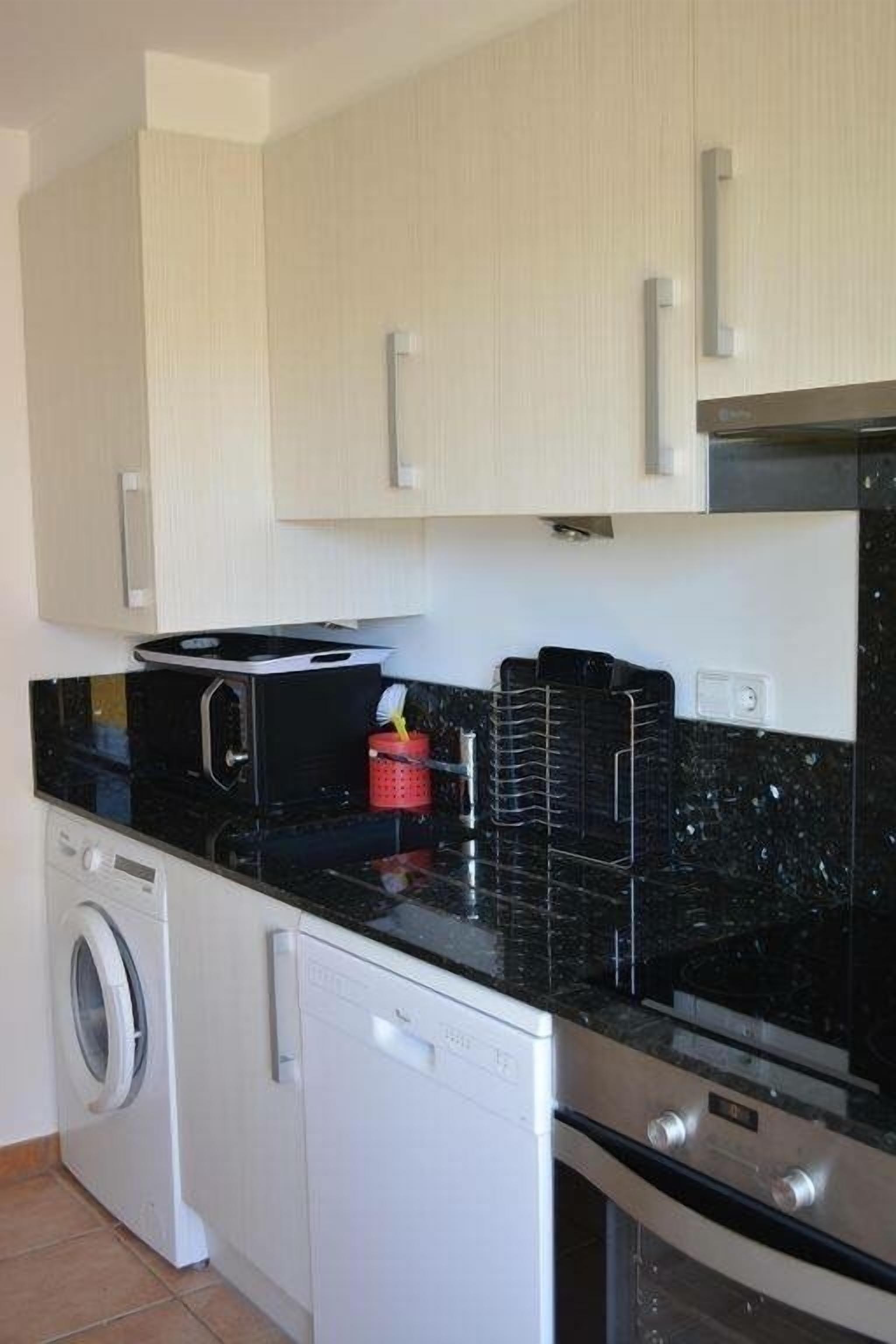 Une cuisine compacte équipée d’un lave-linge, d’un lave-vaisselle, d’un four à micro-ondes et d’une cuisinière.