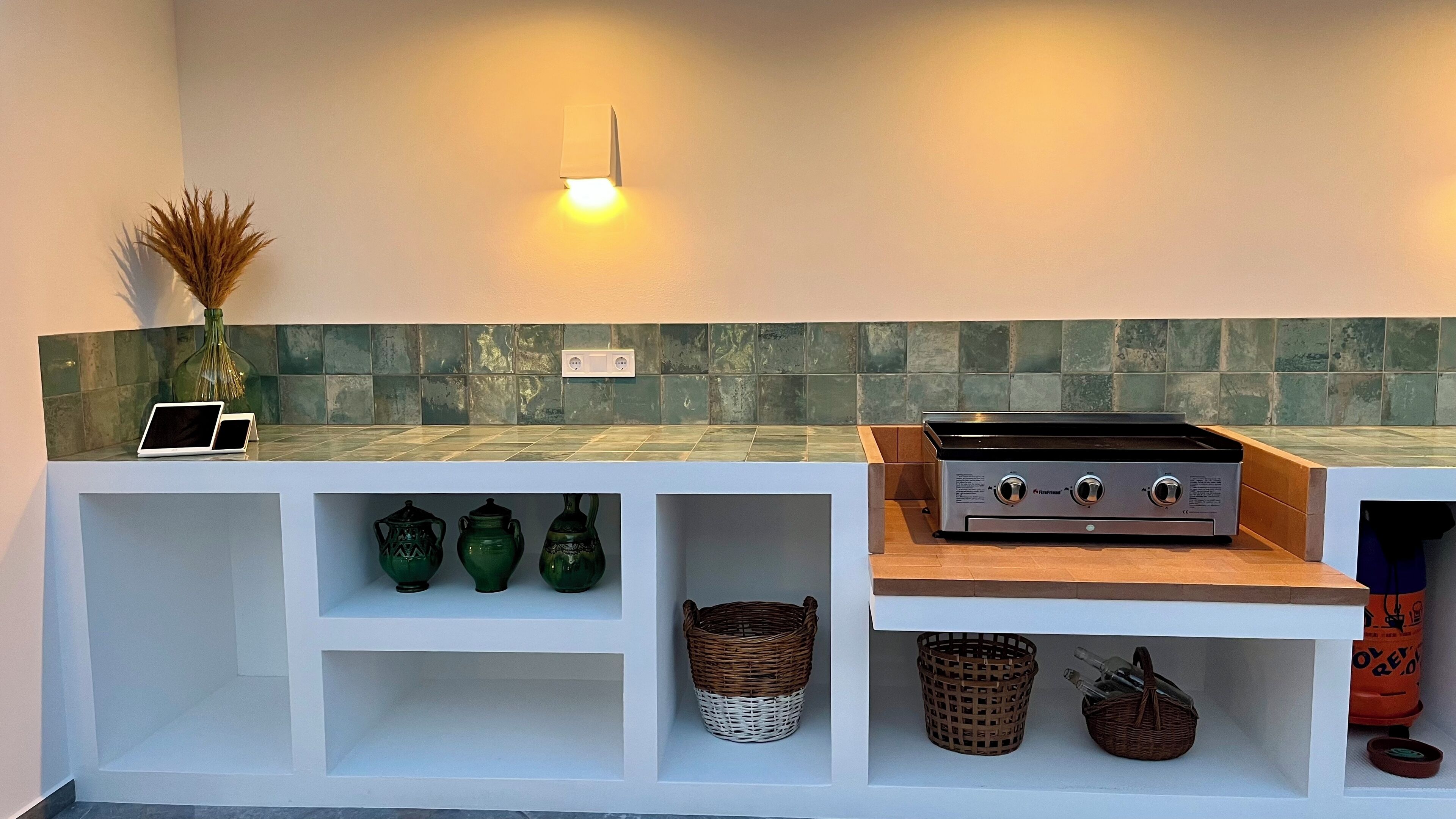 Een moderne keuken met een inbouwfornuis, groene decoratieve vazen en een wit aanrecht.