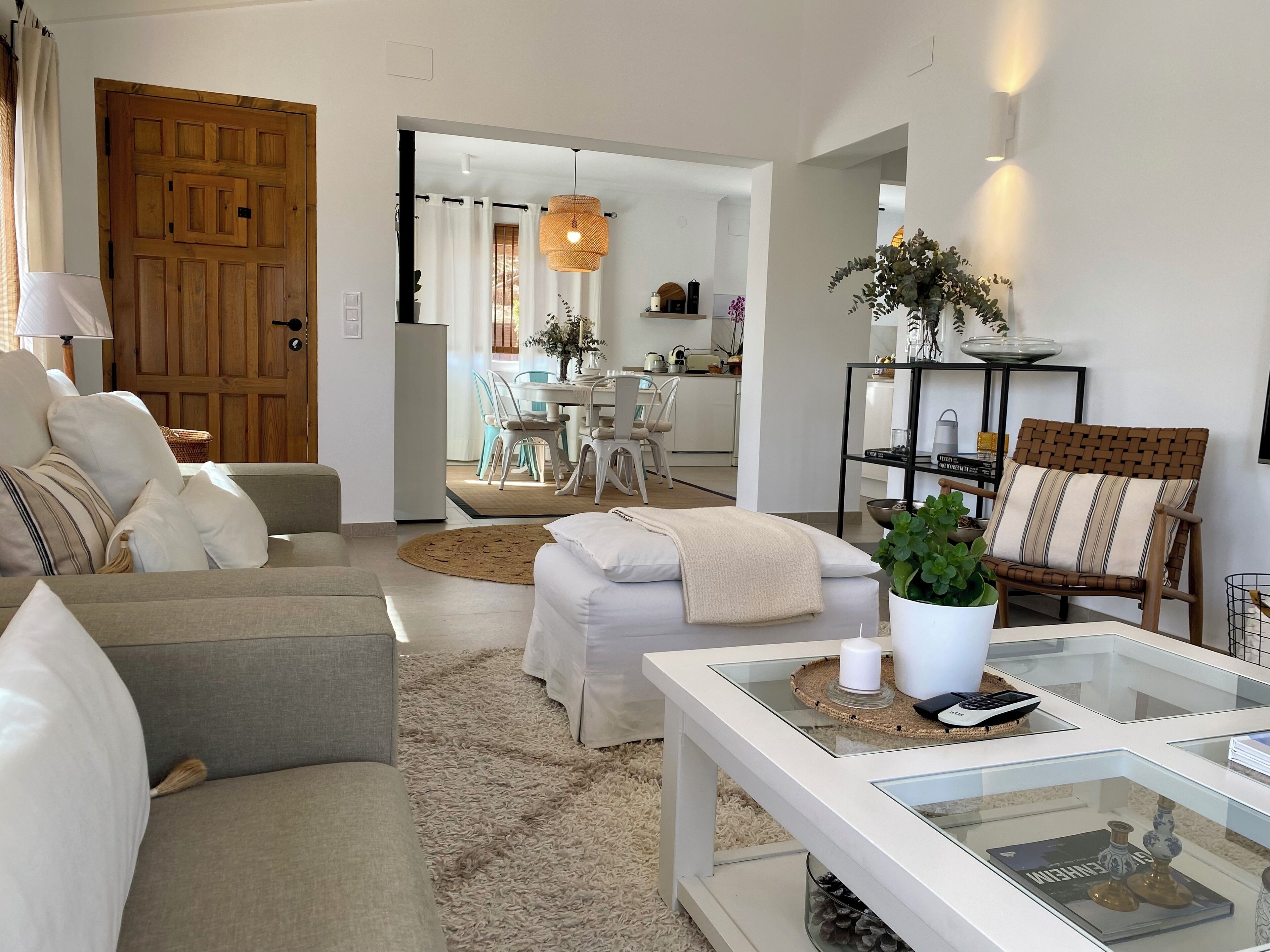 A modern living room with a sofa, a coffee table, and a dining area in the background.
