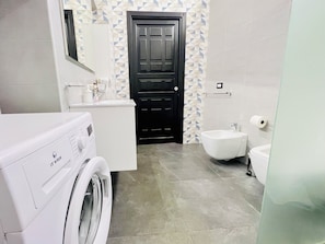 Ein modernes Badezimmer mit Waschmaschine, Bidet und Toilette.