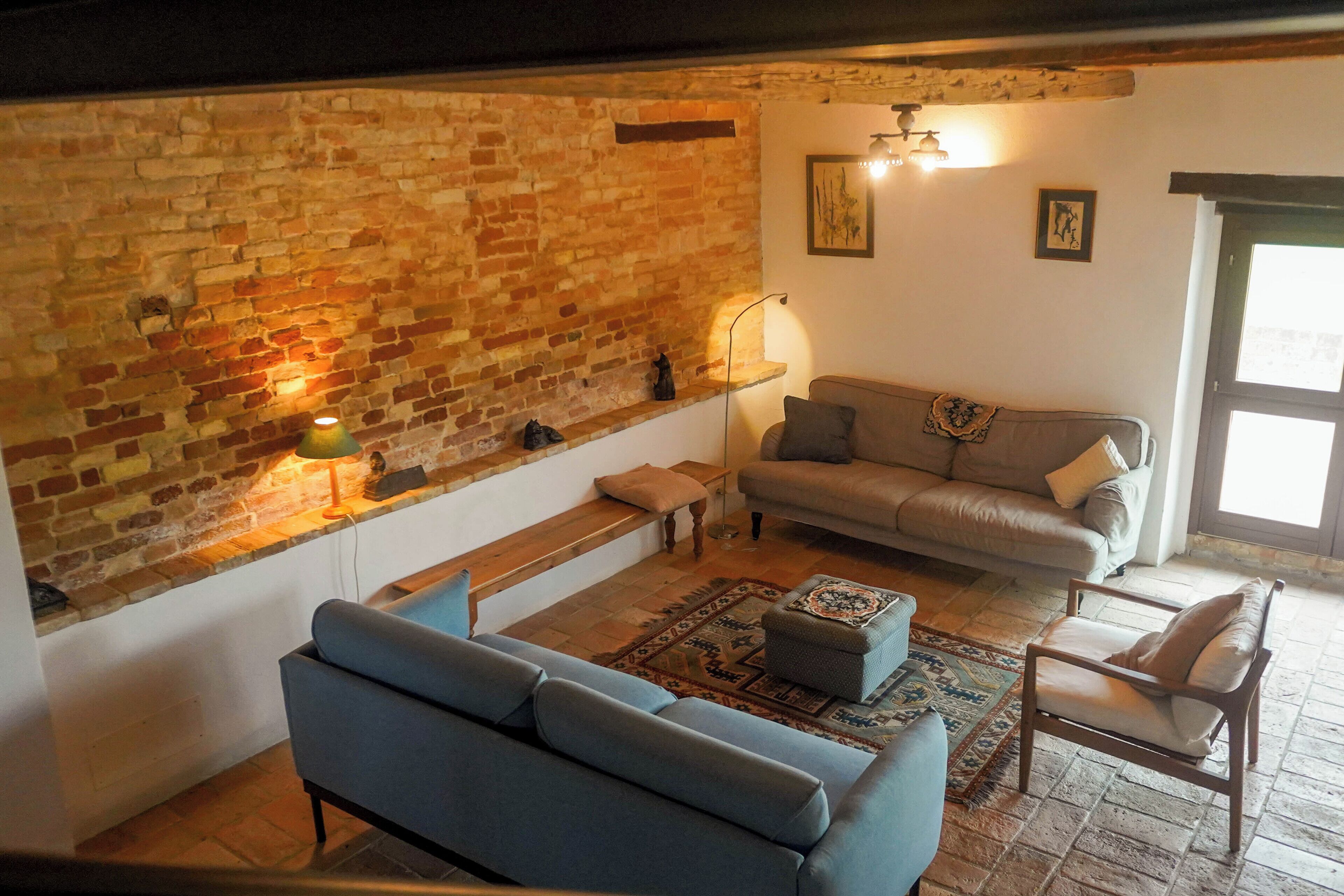 A cozy living room with a brick wall, a sofa, a chair, and a coffee table.