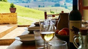 A table set for dining with wine glasses and a bottle of wine, overlooking a scenic hillside.