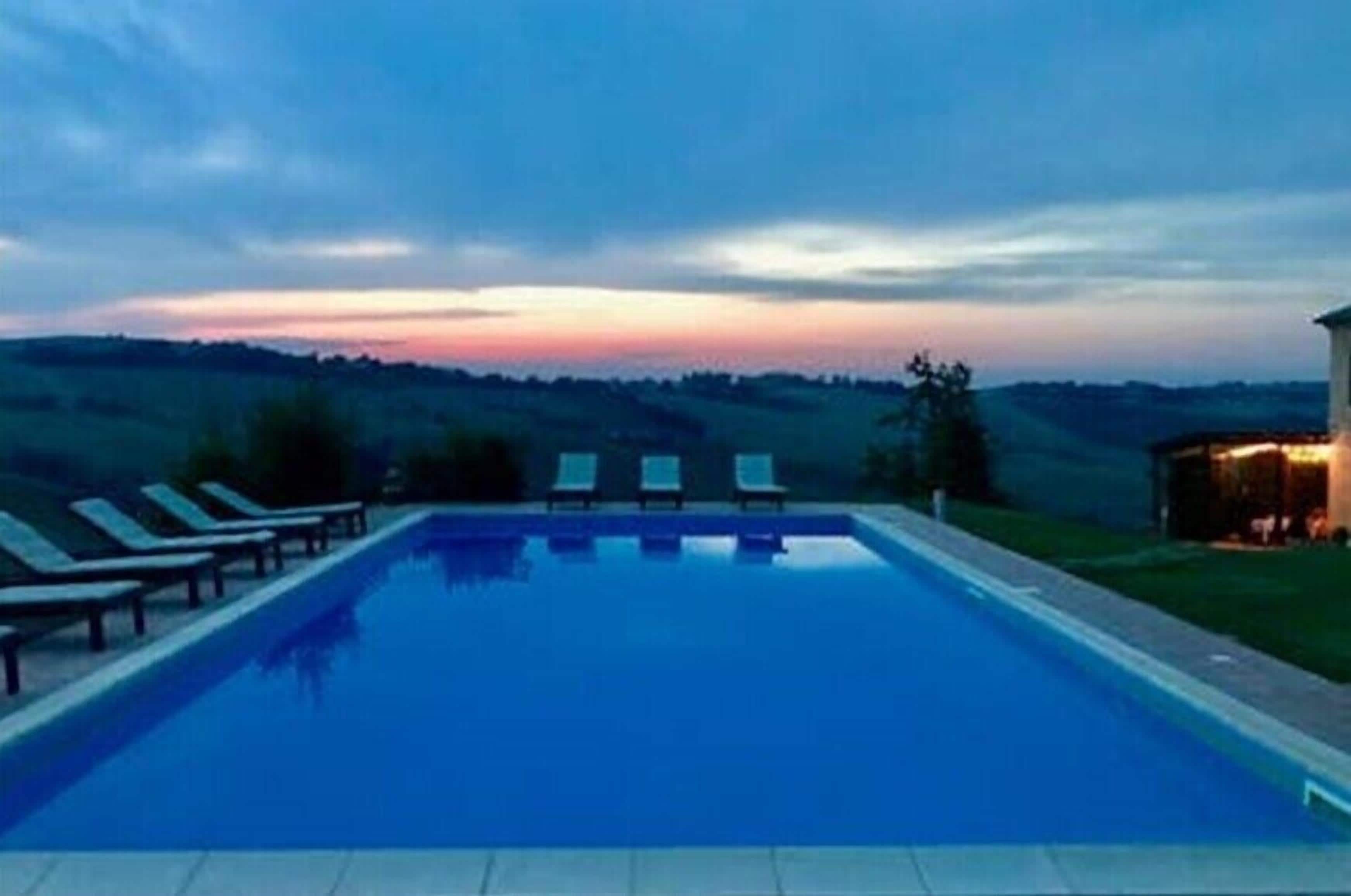 A rectangular swimming pool with lounge chairs aligned along its length.