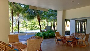 A spacious outdoor seating area with wicker chairs and a view of palm trees. - Seaside, heart of Batu Ferringhi beach, luxury home stay  (Tanjung Bungah)