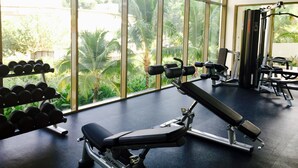 A gym with large windows, weight machines, and dumbbells. - Seaside, heart of Batu Ferringhi beach, luxury home stay  (Tanjung Bungah)