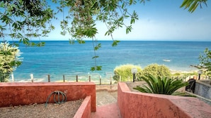Un escalier menant à un balcon d’où l’on peut admirer une vue sur la côte, avec un ciel dégagé.