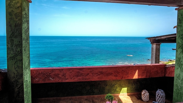 Une vue depuis un balcon abrité, donnant sur une mer turquoise.