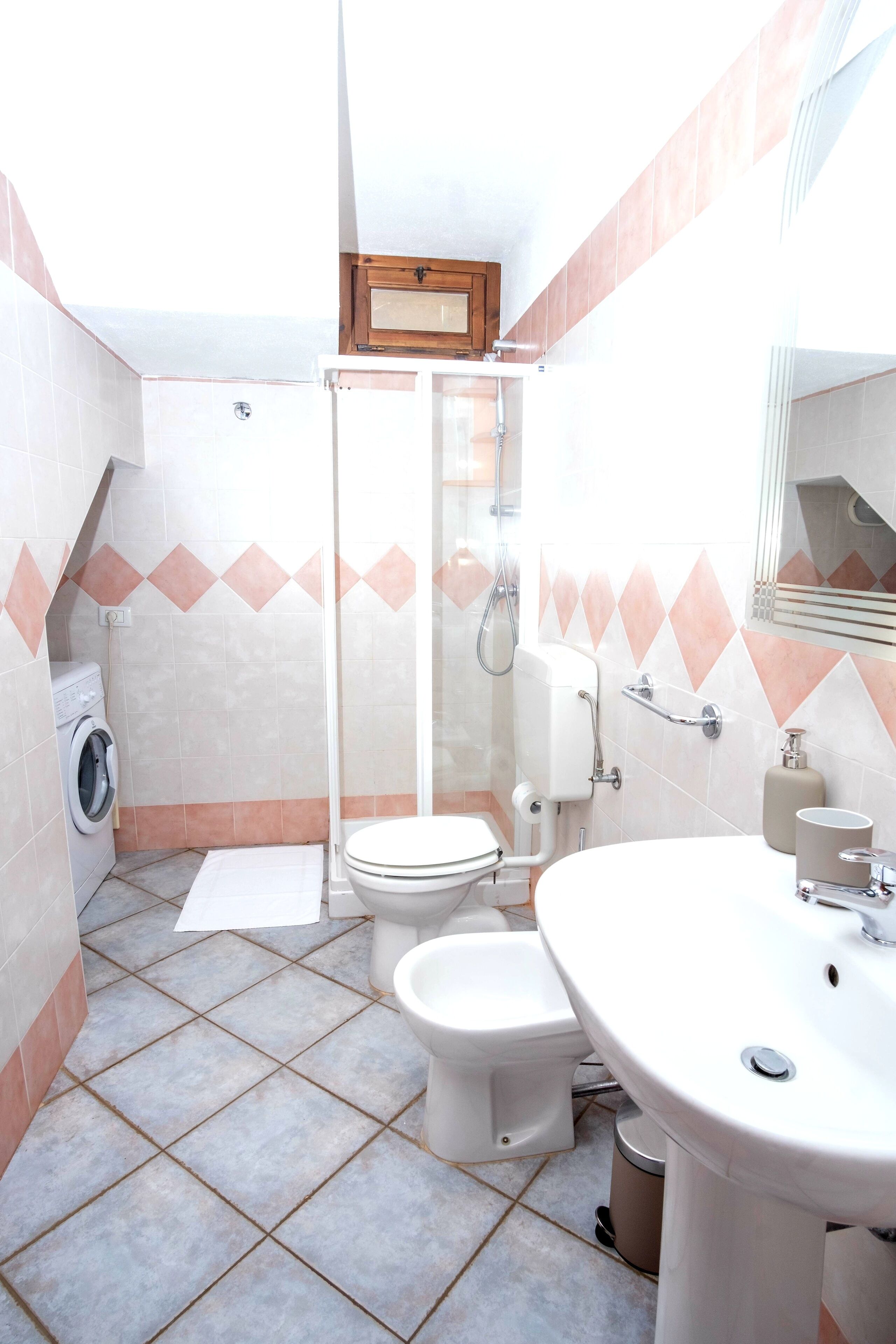 Un baño equipado con lavadora, inodoro, ducha y lavamanos.