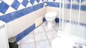Une salle de bain avec des toilettes, un lavabo et une douche.