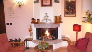 Una sala de estar con chimenea, dos sofás, una mesa de centro y un jarrón decorativo.