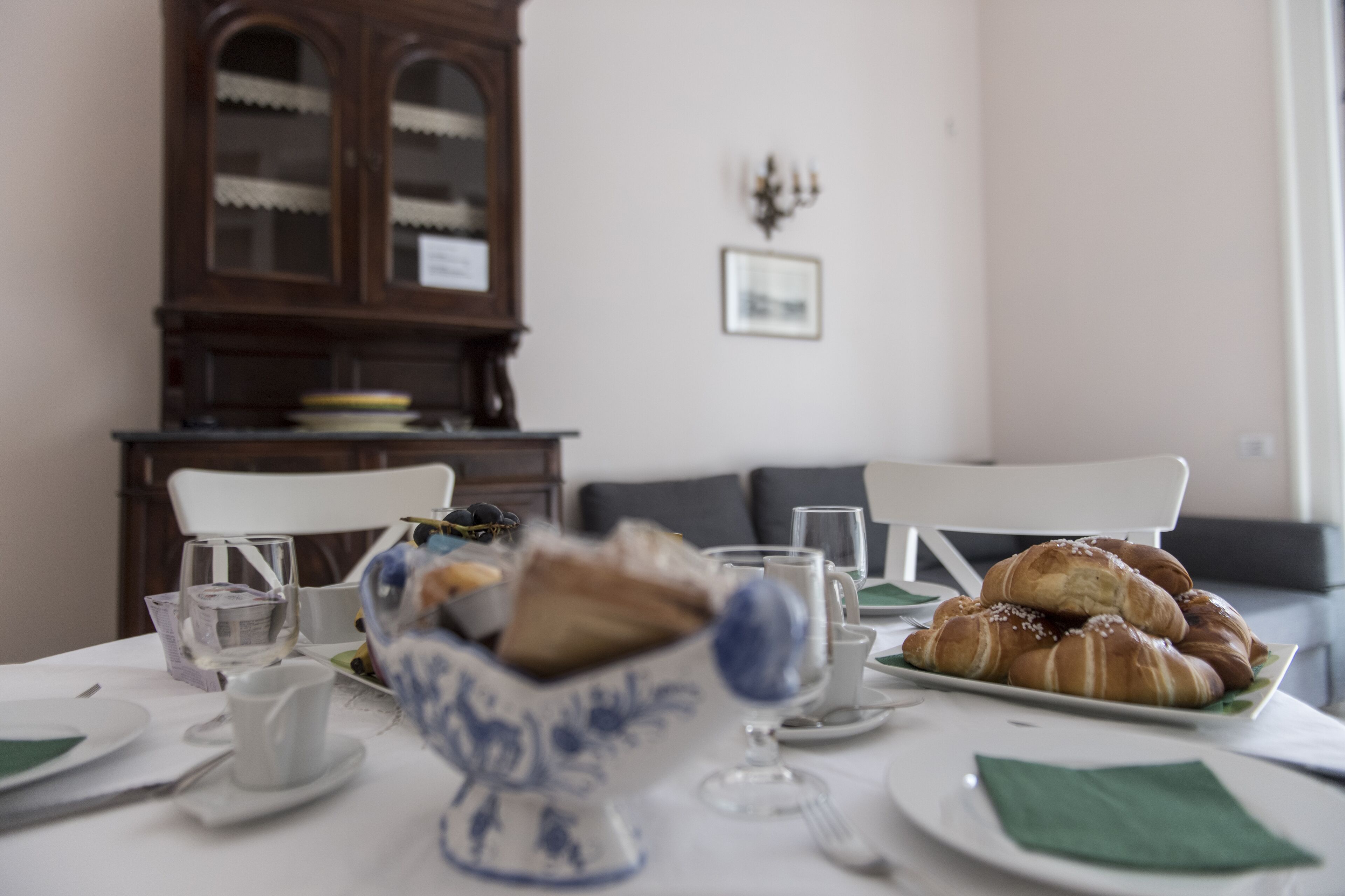 A dining table set with plates, glasses, and a bowl of bread.