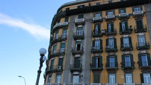 Un edificio de varios pisos con balcones, ventanas grandes y una farola.