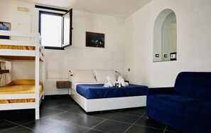 A room with a bunk bed, a single bed with a blue bedspread, a blue armchair, a wall-mounted mirror, and a small painting. - Independent apartment with sea view terrace in the historic center of Lipari (Lipari)