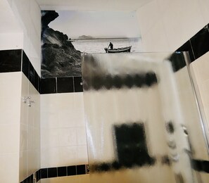 A bathroom with a large mirror, tiled walls, and a view of a rocky coastline with a boat. - Independent apartment with sea view terrace in the historic center of Lipari (Lipari)