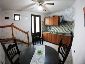 A compact kitchen with wooden cabinets, a tiled backsplash, and a ceiling fan. - Independent apartment with sea view terrace in the historic center of Lipari (Lipari)