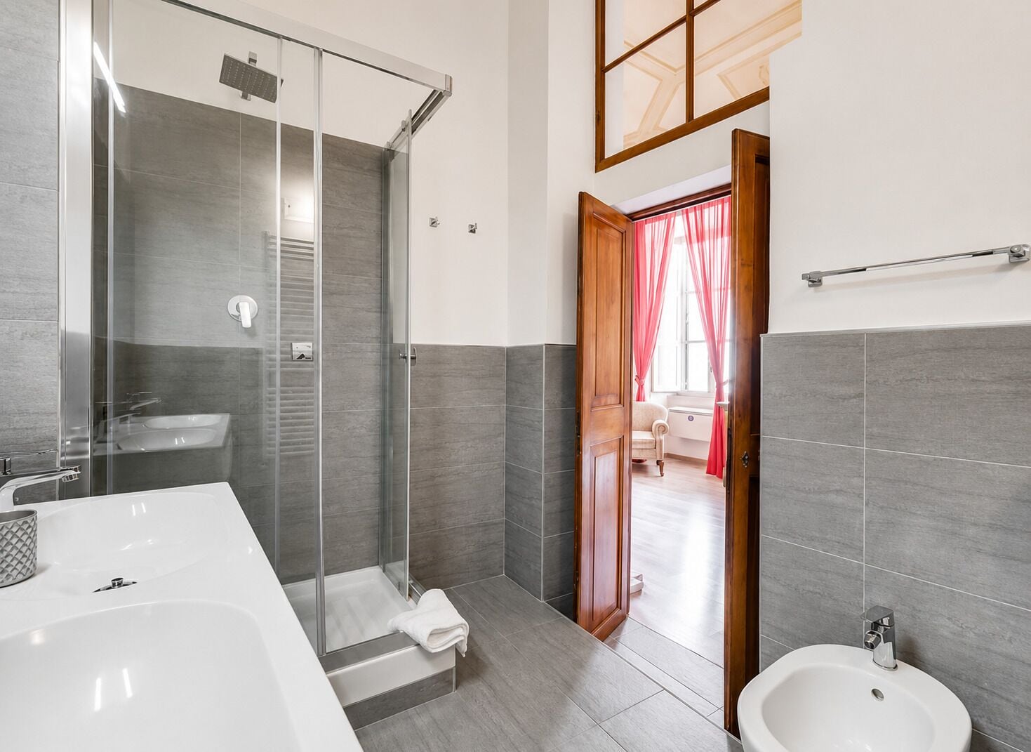 A modern bathroom with a glass-enclosed shower, a large white bathtub, and a separate sink.
