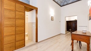 Una stanza con un armadio in legno, un tavolo da pranzo e vista su un bagno attraverso una porta aperta.