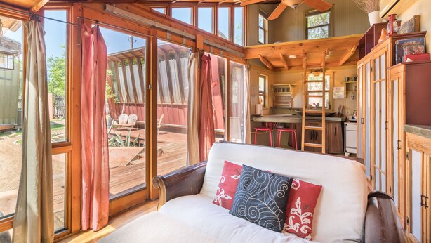 Un chalet confortable avec un grand lit, des poutres en bois et une vue sur la terrasse.