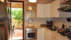 A compact kitchen with a built-in oven, a sink, and a window overlooking a garden. - Villa 200 mt. from the sea (San Vito Lo Capo)