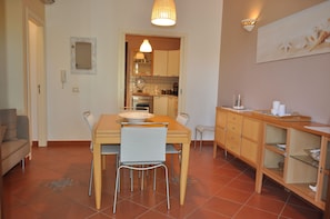 A compact kitchen with a dining table, chairs, and a small island with a sink.