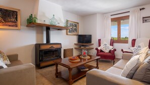 A living room with a fireplace, sofa, armchair, and a television. - FINCA MARINA  VT/121 ref. VP11 (Pollensa / Pollença)
