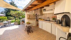 An outdoor kitchen with a stone tile floor, a table with chairs, and a pergola overhead. - FINCA MARINA  VT/121 ref. VP11 (Pollensa / Pollença)