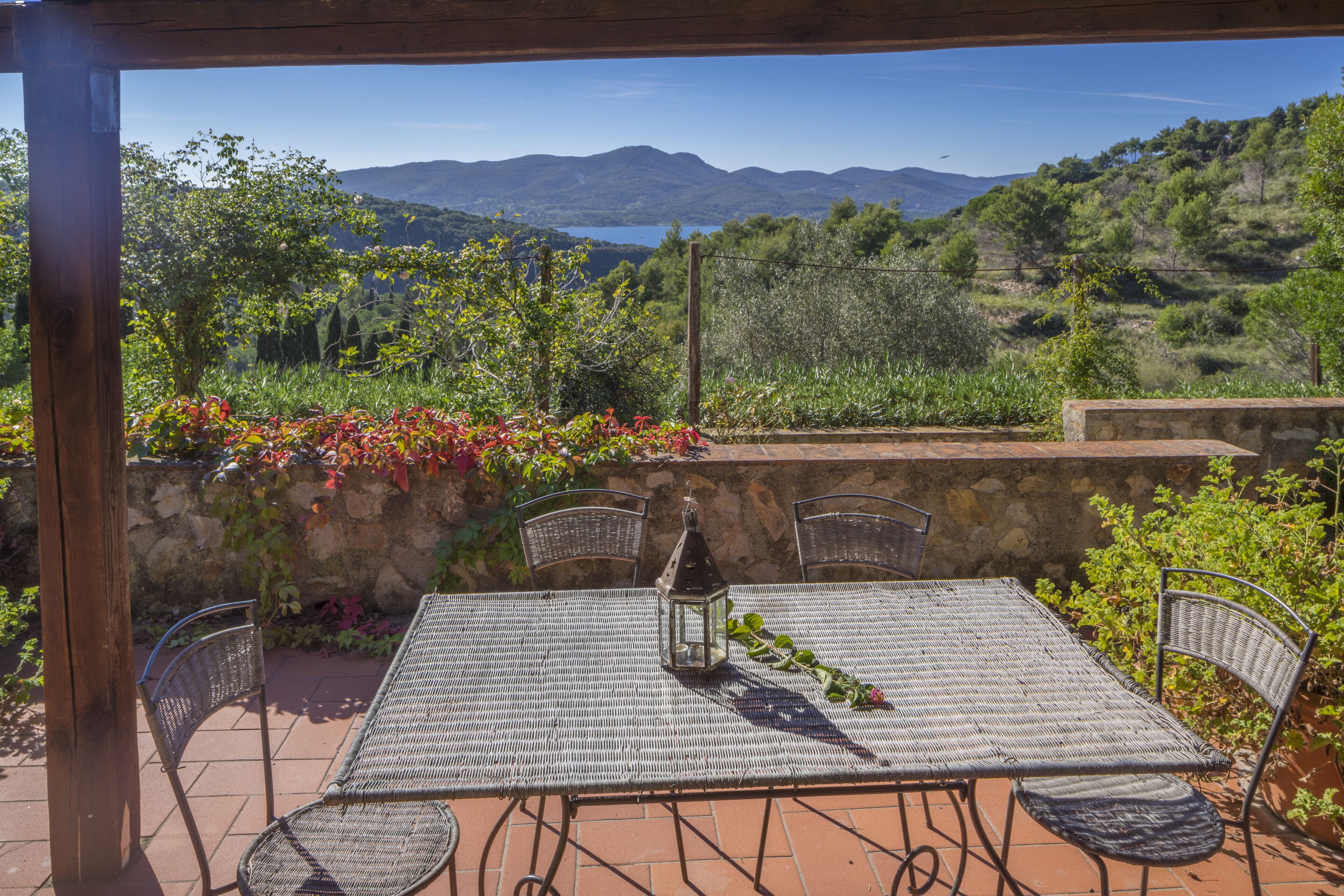 Eine Terrasse im Freien mit Tisch, Stühlen, einer Laterne und Blick auf Berge und einen See.